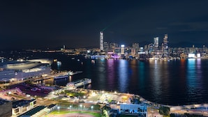 A nighttime cityscape with a prominent skyscraper, waterfront, and a stadium. - Hong Kong Harbour Hotel (Hong Kong Island)