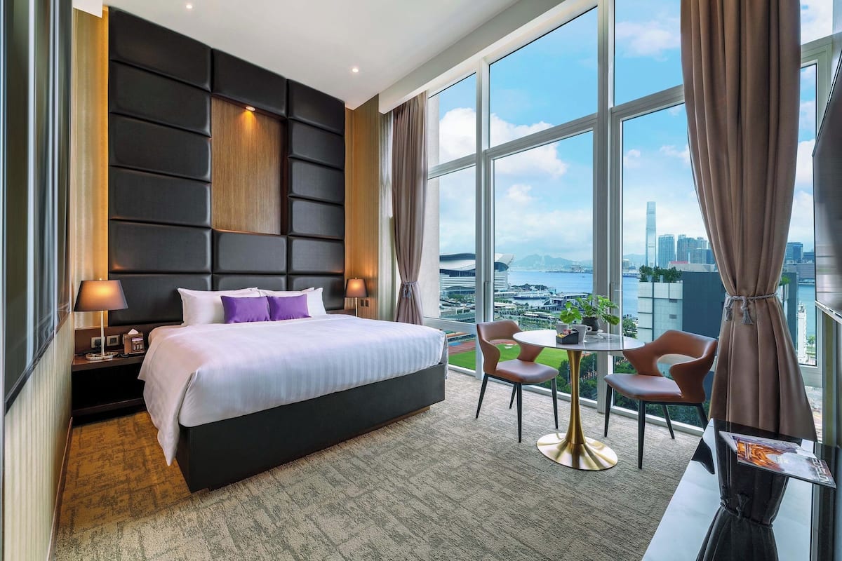 Quarto de hotel moderno com uma cama grande, uma escrivaninha e vista para a cidade.