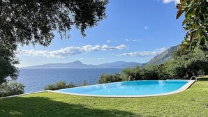 A swimming pool with a view of the sea and mountains.