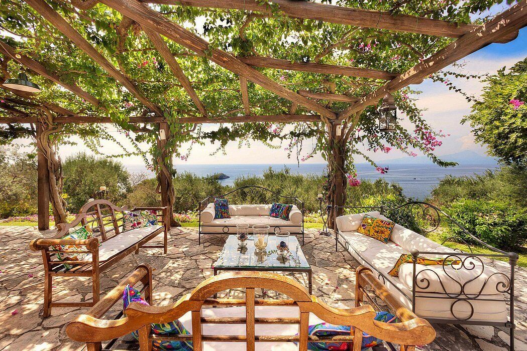 An outdoor seating area with wooden furniture and a view of the sea.