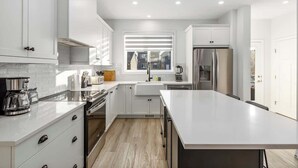 A modern kitchen with white cabinetry, a large island, and stainless steel appliances.