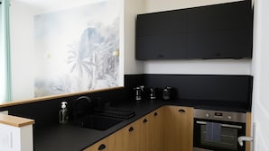 Eine moderne Küche mit schwarzen Arbeitsplatten, Holzschränken, einem Einbauofen und einer Kaffeemaschine.