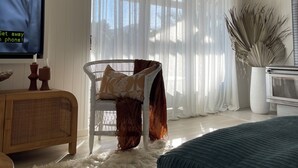Een moderne woonkamer met een groot raam, een televisie, een bank en een decoratieve plant.
