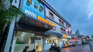 A hotel named "Hotel Beverly Palace" with a glass facade, a visible restaurant, and parked scooters outside. - Beverly Palace Kozhikode (Kozhikode)