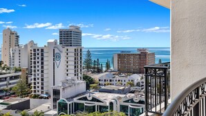 A high-rise hotel with a view of the ocean, featuring a prominent logo on the building.