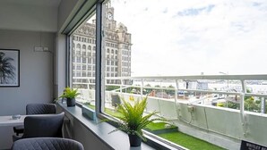 Un espacio de oficina moderno con un ventanal grande que da a un paisaje urbano y un balcón pequeño con vistas a la ciudad.