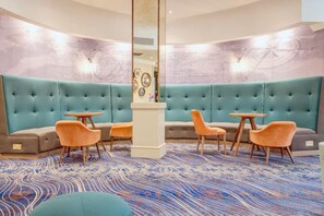 Un hall d’hôtel doté d’un espace salon aux lignes courbes, d’un pilier central et d’un tapis à motifs.