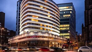 Hotel Atlantic Tower con fachada curva, varios pisos y ventanas iluminadas.