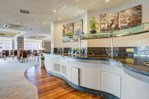 Un hall d’hôtel moderne avec un comptoir d’accueil incurvé, un espace salon et des œuvres d’art accrochées aux murs.
