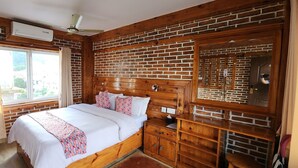 A bedroom with a wooden headboard, a large window, a bedside table, and a nightstand. - Kiwi Backpackers Hostel (Pokhara)