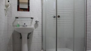 A bathroom with a white pedestal sink, a glass-enclosed shower, and a toilet. - Kiwi Backpackers Hostel (Pokhara)