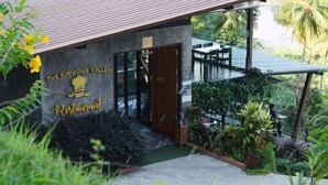 Een restaurant genaamd 'The Kiriwong Valley Restaurant' met uitzicht op een rivier en palmbomen.