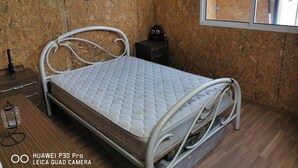 A bed with a quilted mattress in a room with wooden walls and a window. - Bungalow by the sea Cozy We accept pets (Costa da Caparica)