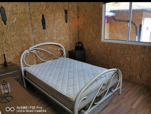 A bed with a quilted mattress in a room with wooden walls and a window. - Bungalow by the sea Cozy We accept pets (Costa da Caparica)