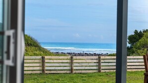 A view of the ocean from a wooden fence with a grassy foreground.