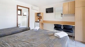 A hotel room with two beds, a desk with a computer, a TV, and wooden cabinets. - Palm Valley Motel (Tarro)