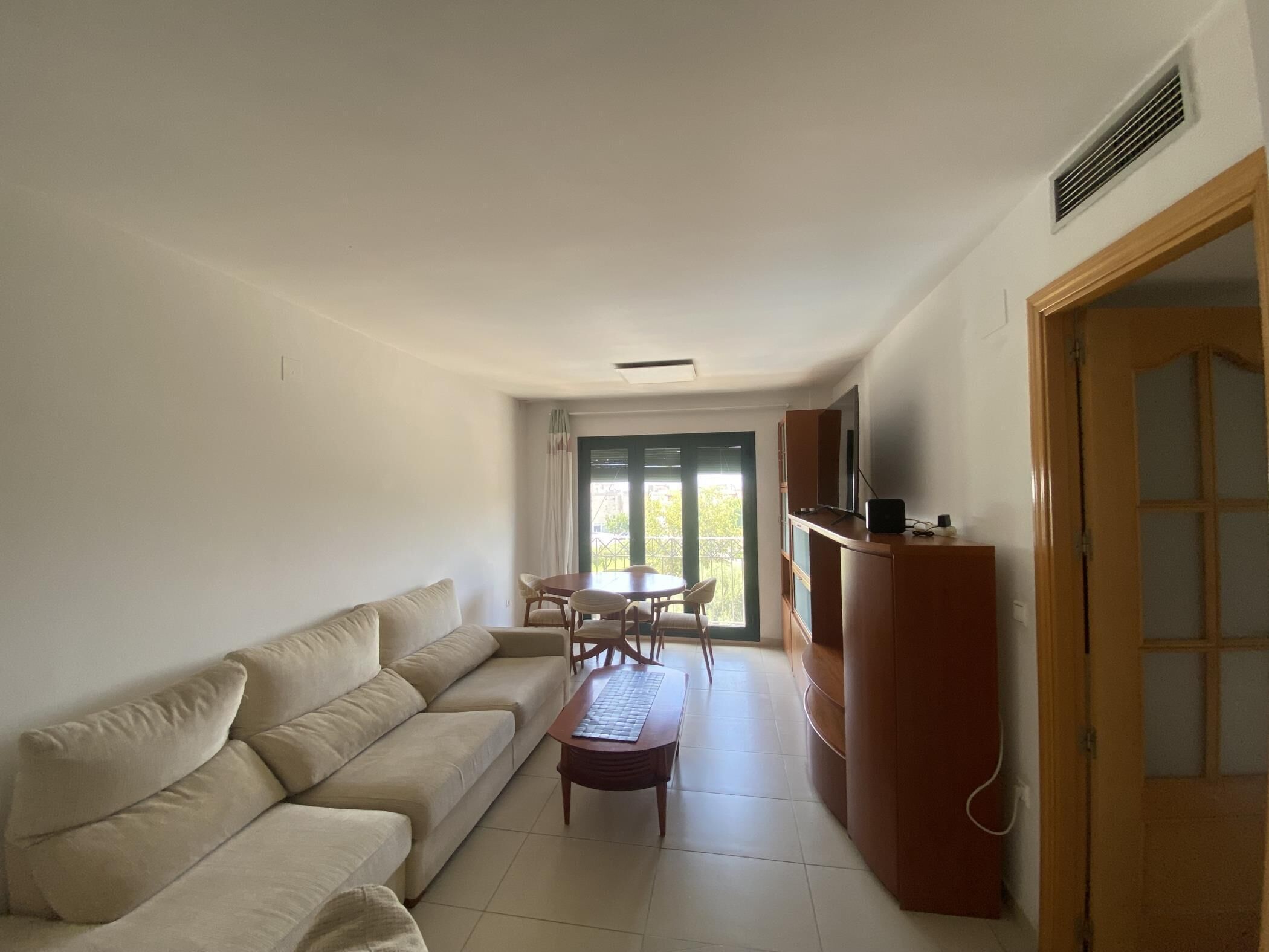 A living room with a sofa, a small table, and a TV on a wooden stand.