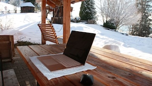 Una mesa de madera con una computadora portátil y una taza, ubicada al aire libre en un entorno nevado.