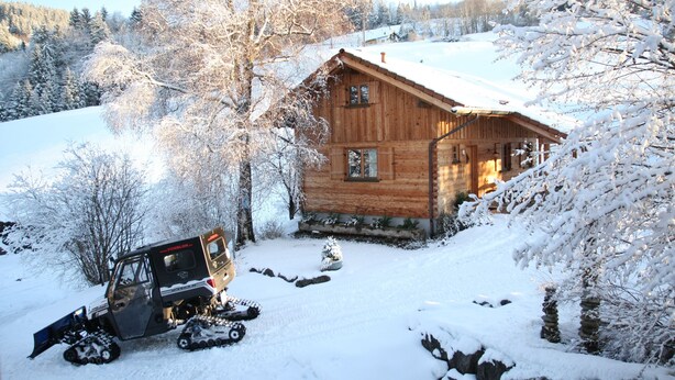 Una cabaña de madera con techo nevado, un trineo y un paisaje cubierto de nieve.