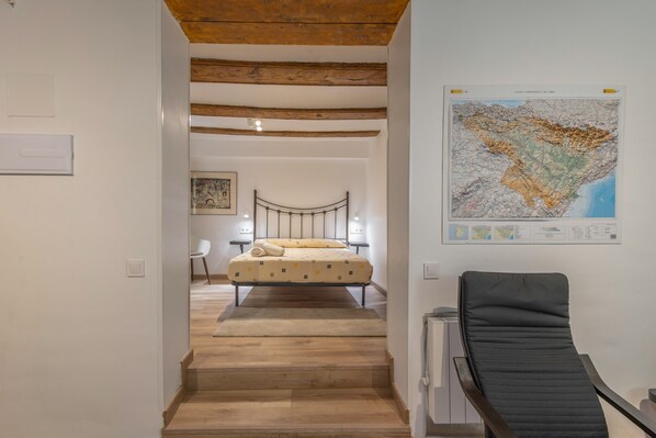 Un dormitorio con cama, una silla, un mapa en la pared y una escalera.