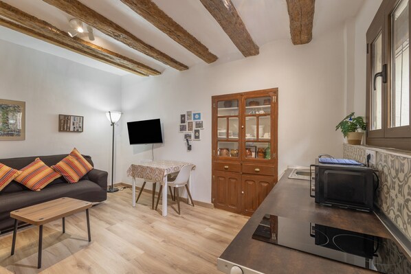 A living room with a sofa, a table, a TV, a cabinet, and a microwave.