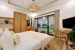 Een moderne hotelkamer met een groot bed, een bureau, een stoel, een televisie en een balkon met planten.