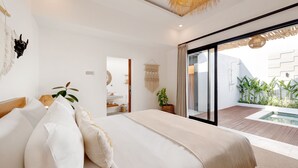 Un dormitorio moderno con una cama grande, un ventanal de vidrio que da a un balcón con plantas y vistas a un edificio.
