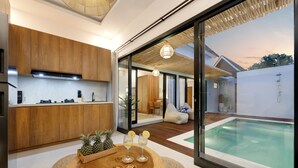 Una cocina moderna con armarios de madera, un comedor con mesa de madera y vistas a una piscina.