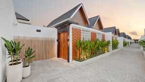 Zona residencial moderna con sendero pavimentado, paredes blancas y detalles de ladrillo.