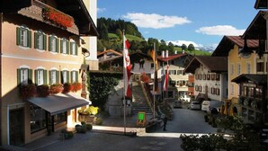 A traditional European village street with buildings, a staircase, and flags.