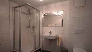 A modern bathroom with a glass-enclosed shower, a white sink, and a toilet.