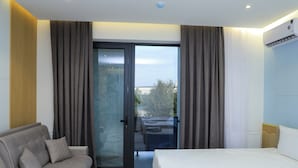 Une chambre d’hôtel comprenant un lit, un canapé, une porte-fenêtre coulissante donnant sur un balcon et un appareil de climatisation fixé au mur.