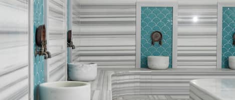 A modern bathroom with marble countertops, a herringbone floor pattern, and a blue-tiled accent wall.