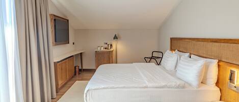 A hotel room with a large bed, a TV mounted on the wall, a bedside table, and a lamp.