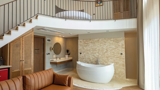 Un vaste espace de vie comprenant une grande baignoire, un escalier et un plafond haut.