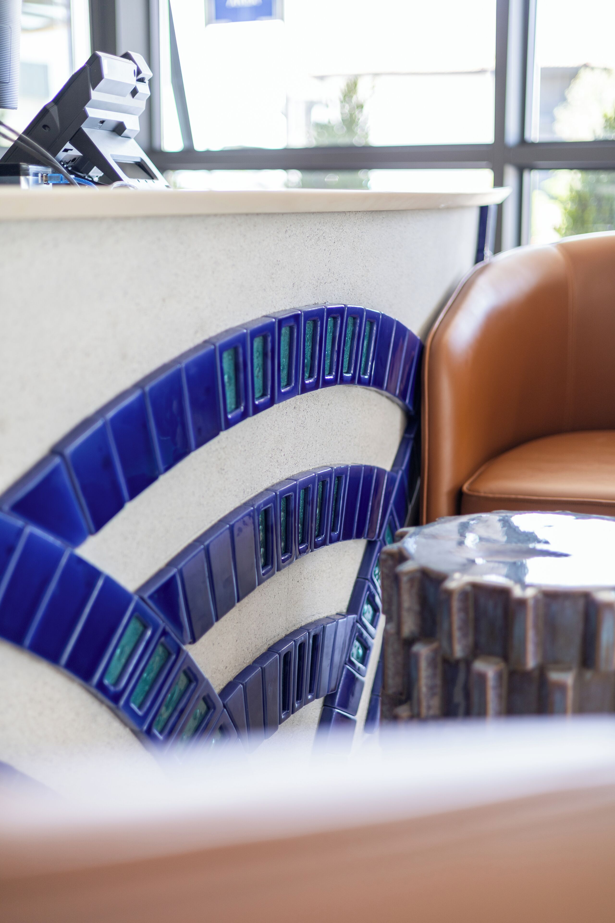 A corner of a room with a curved blue and white tiled wall, a brown leather chair, and a wooden table.