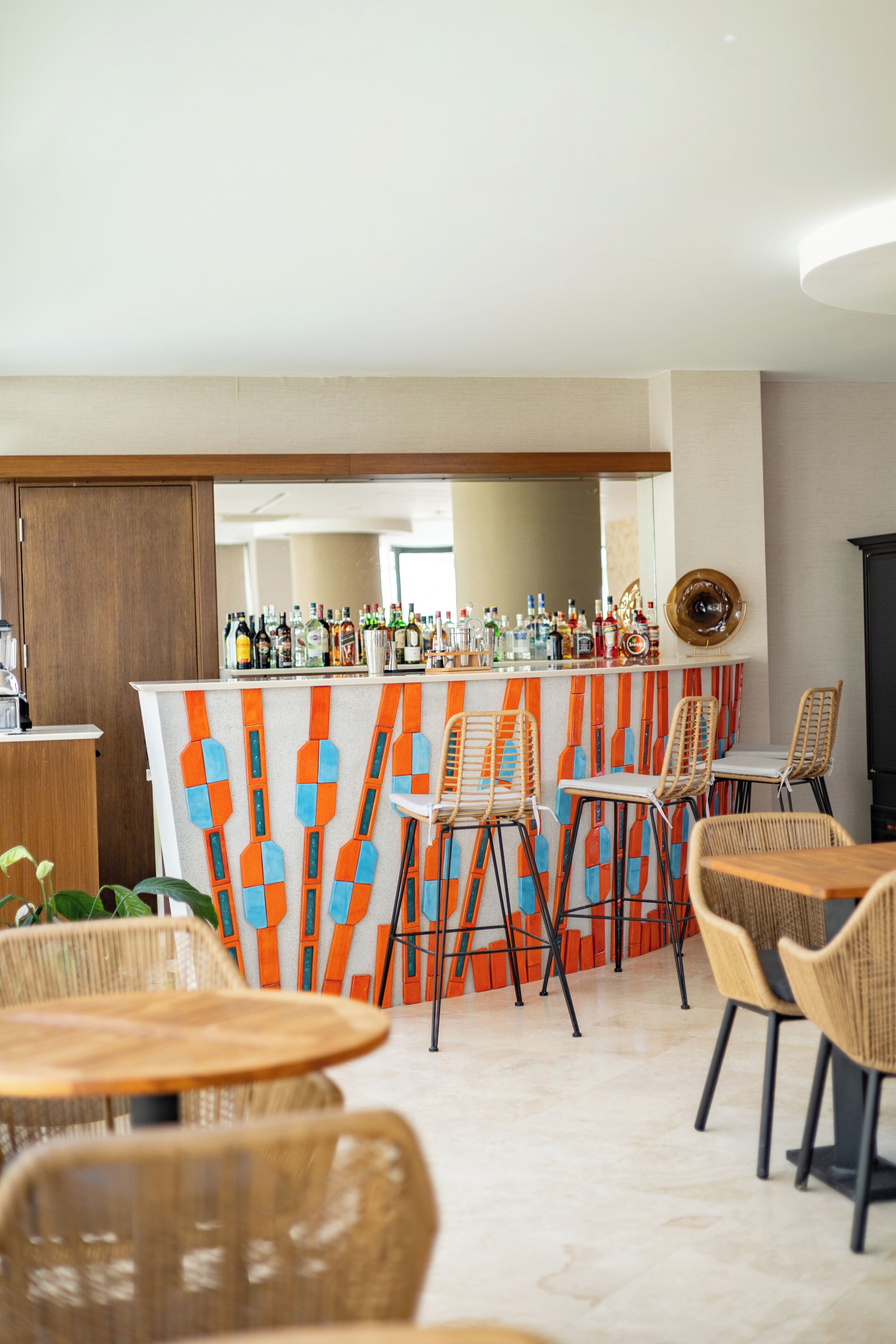 A bar area with a counter, bar stools, and a seating area with round tables and chairs.