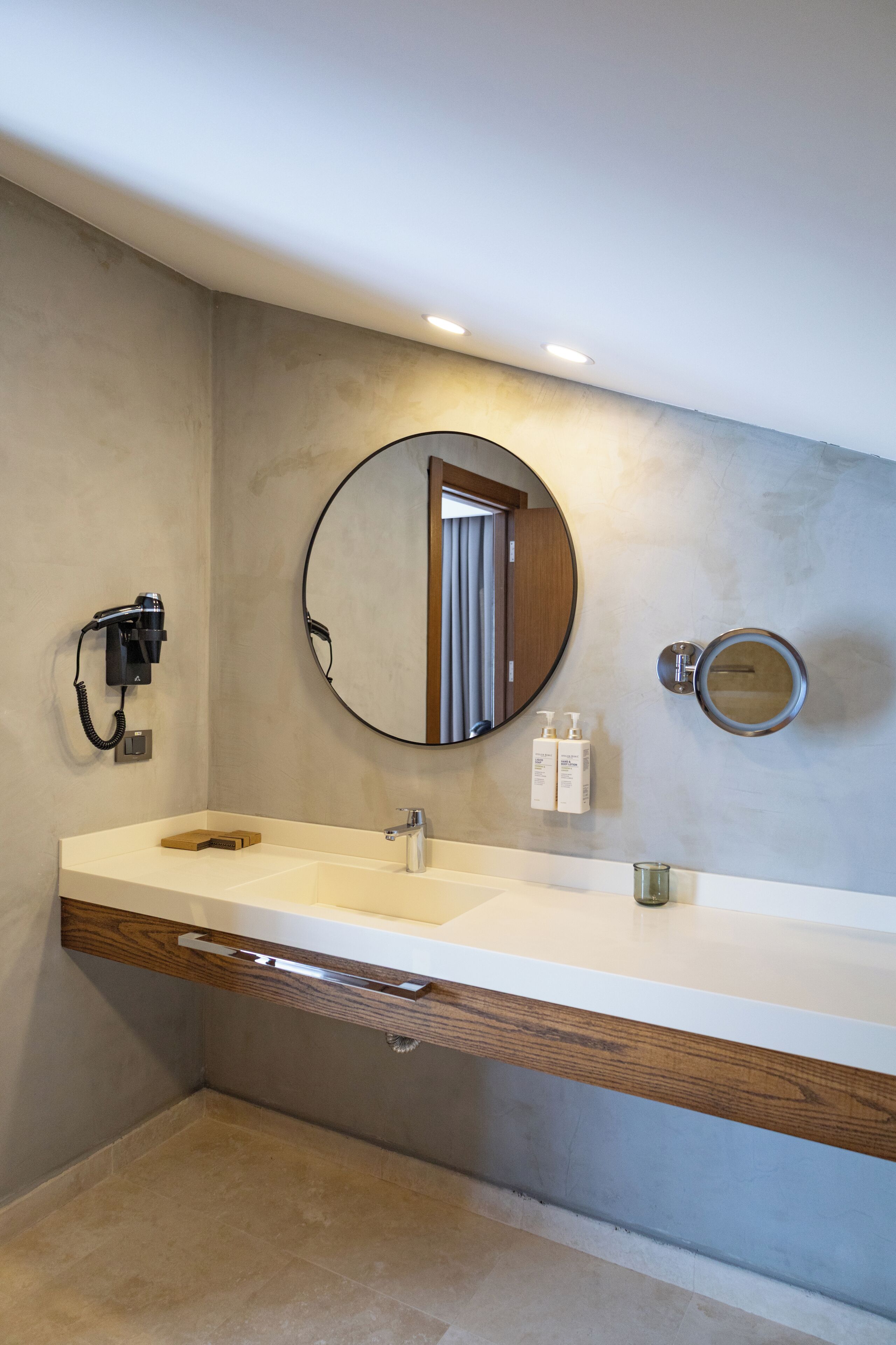 Un baño moderno con un espejo grande, un tocador con encimera de madera y un calentador empotrado.