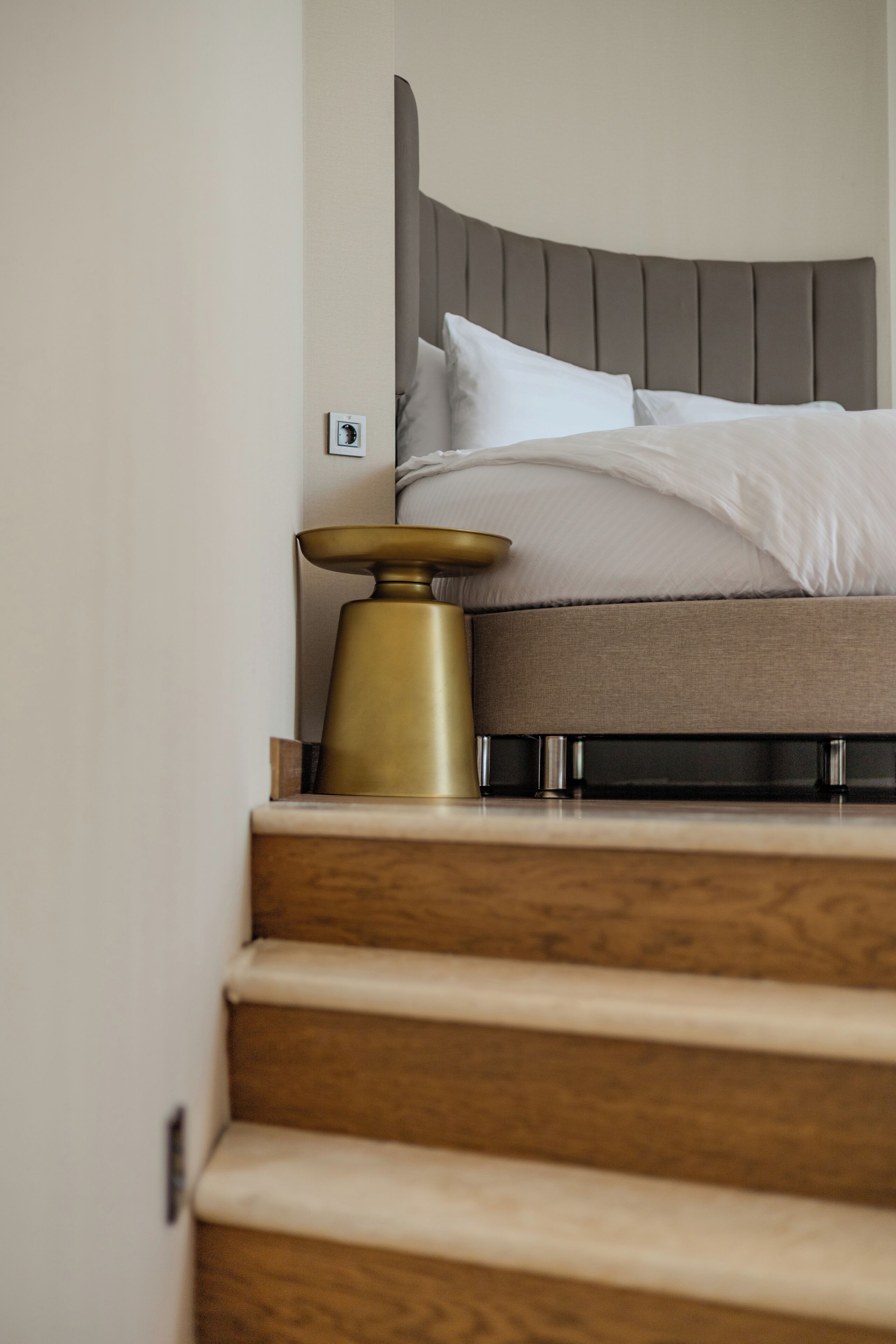 Un dormitorio con cama, mesita de noche y lámpara de pared.