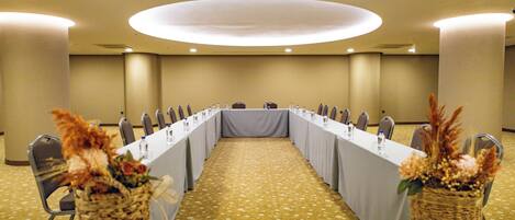 A conference room with a long table, chairs, and a carpeted floor.