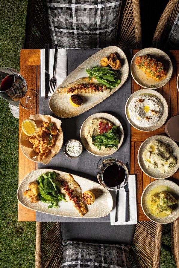 A dining table with various dishes, a wine glass, and cutlery.