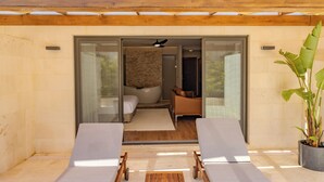 Un espace extérieur moderne aménagé avec deux fauteuils de jardin, une pergola en bois et un pot de fleurs.