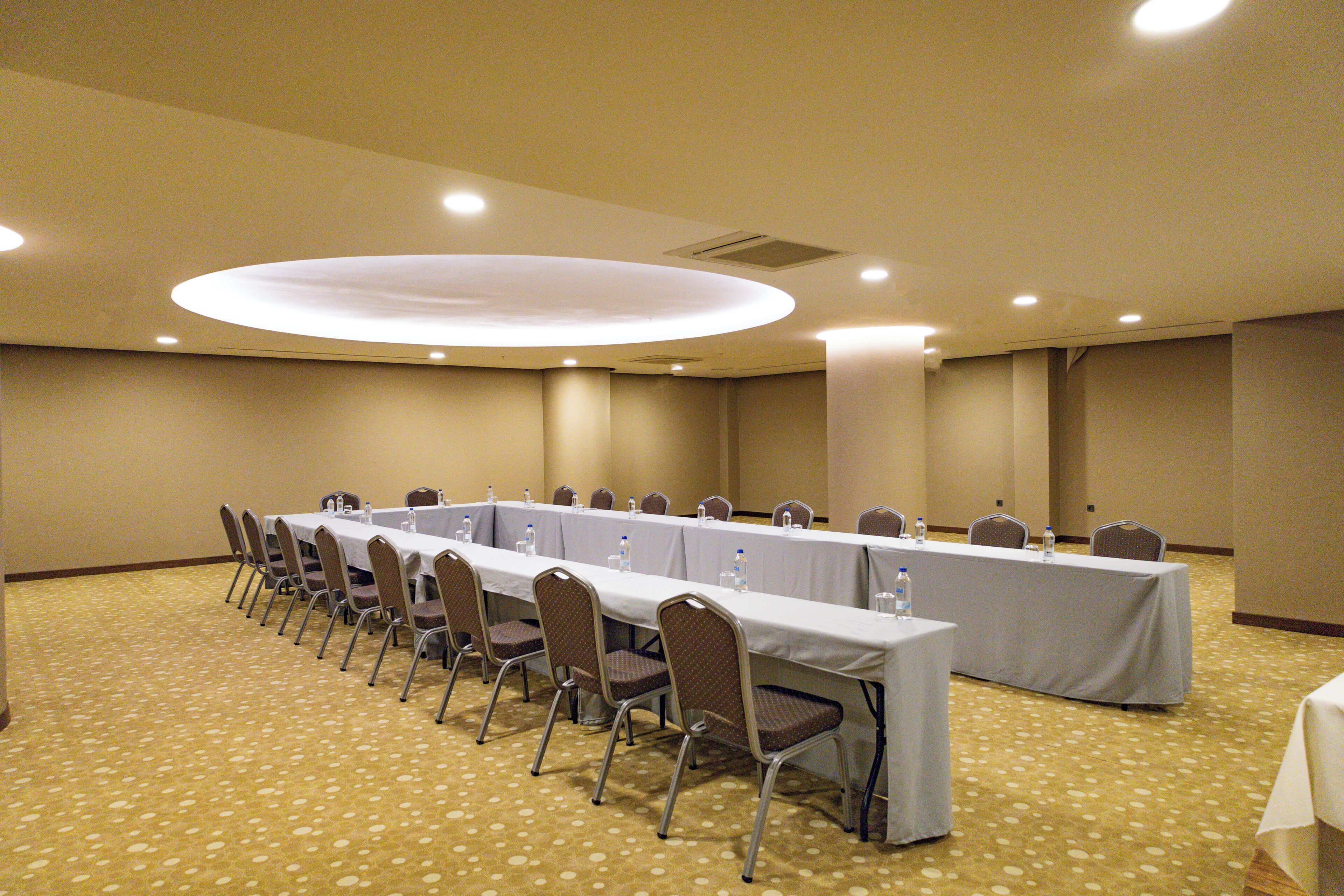 Una sala conferenze con un lungo tavolo, sedie e bottiglie d'acqua.