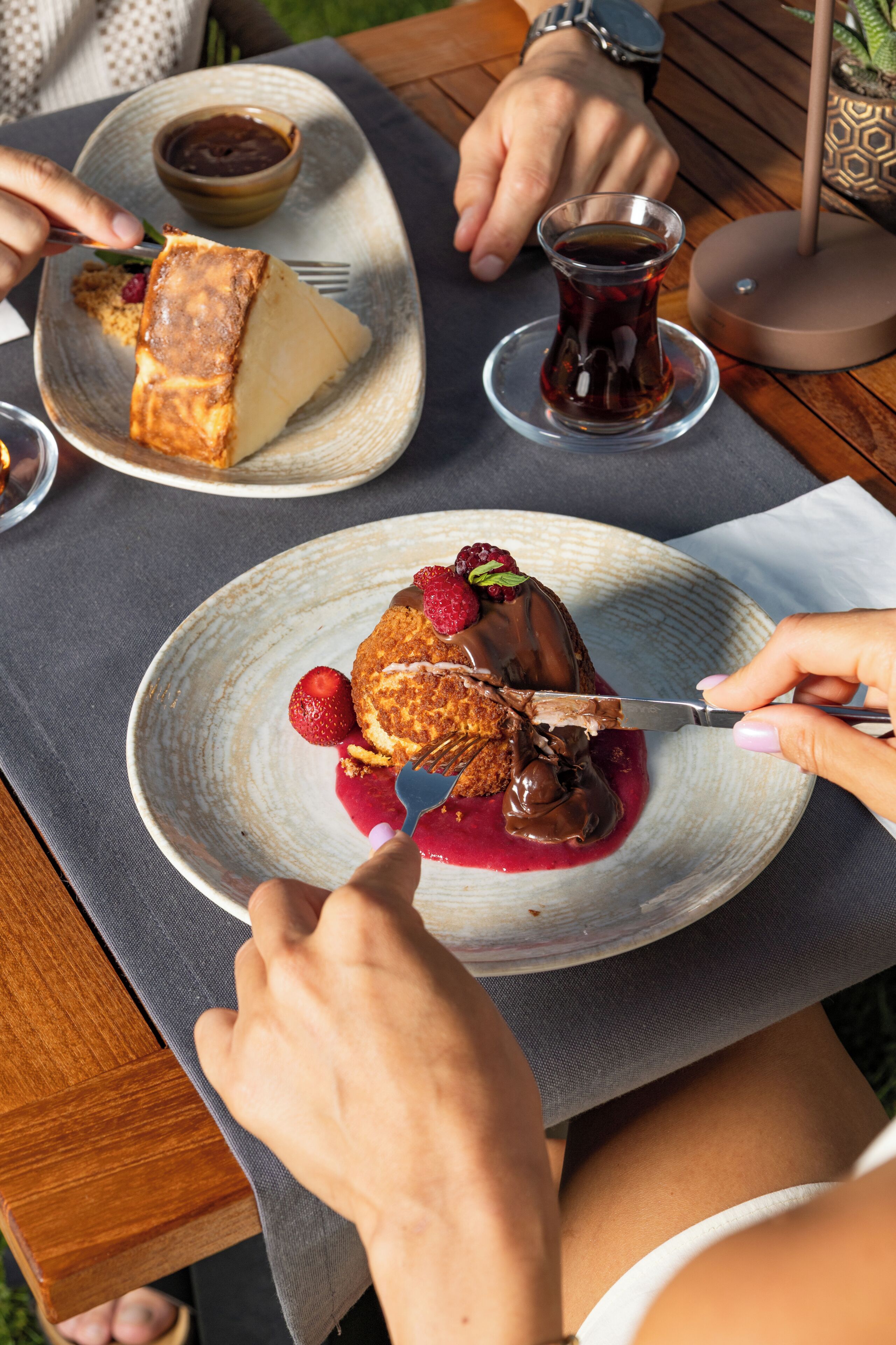 Una mesa con un plato de postre, una taza de té y un tazón pequeño de salsa de chocolate.