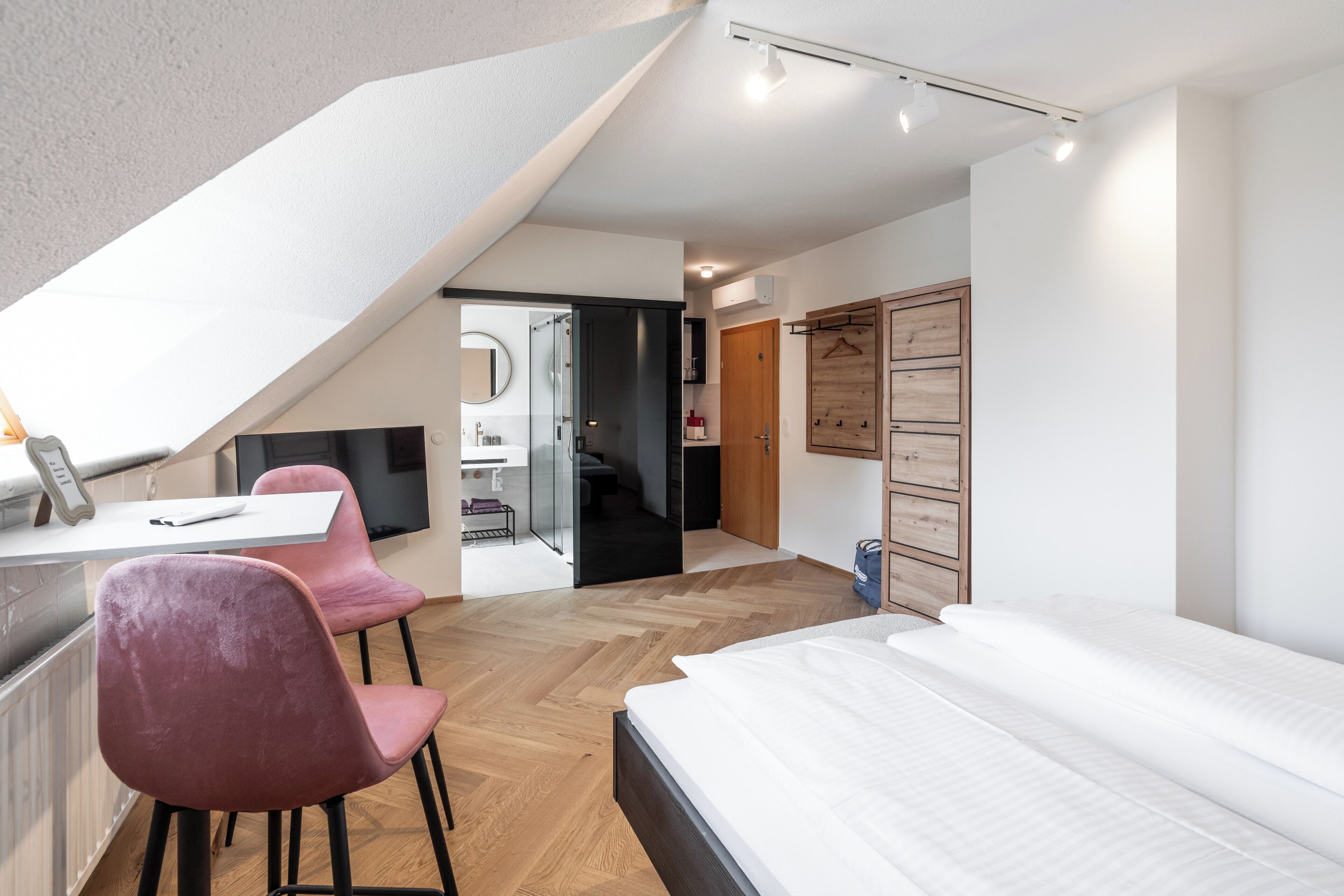 Un dormitorio moderno con una cama grande, un escritorio con silla y un vestidor.
