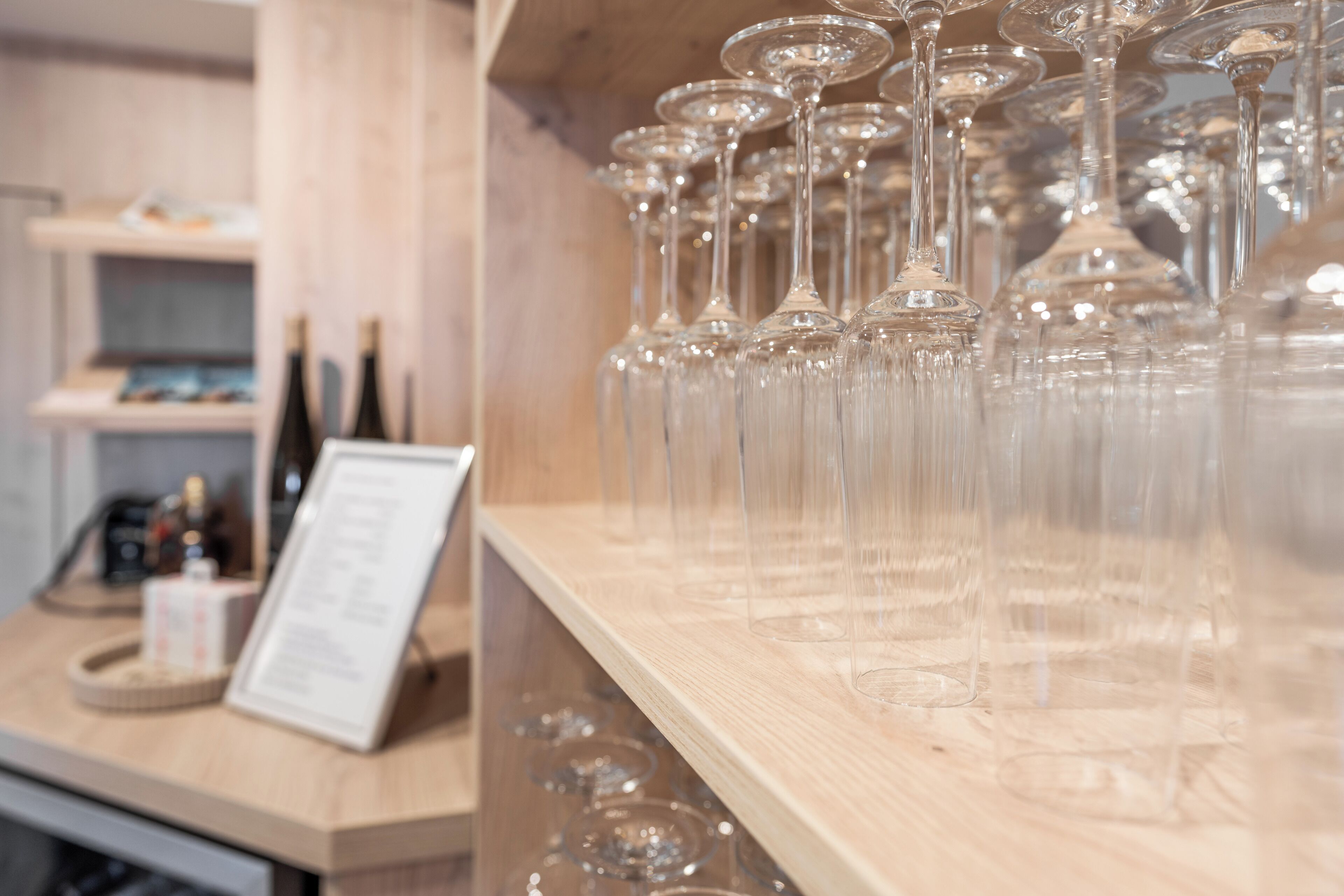 Un espace bar avec de nombreux verres à vin et des bouteilles disposées sur des étagères.