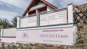 Letrero de SISTER'S Haus con un mensaje de bienvenida.