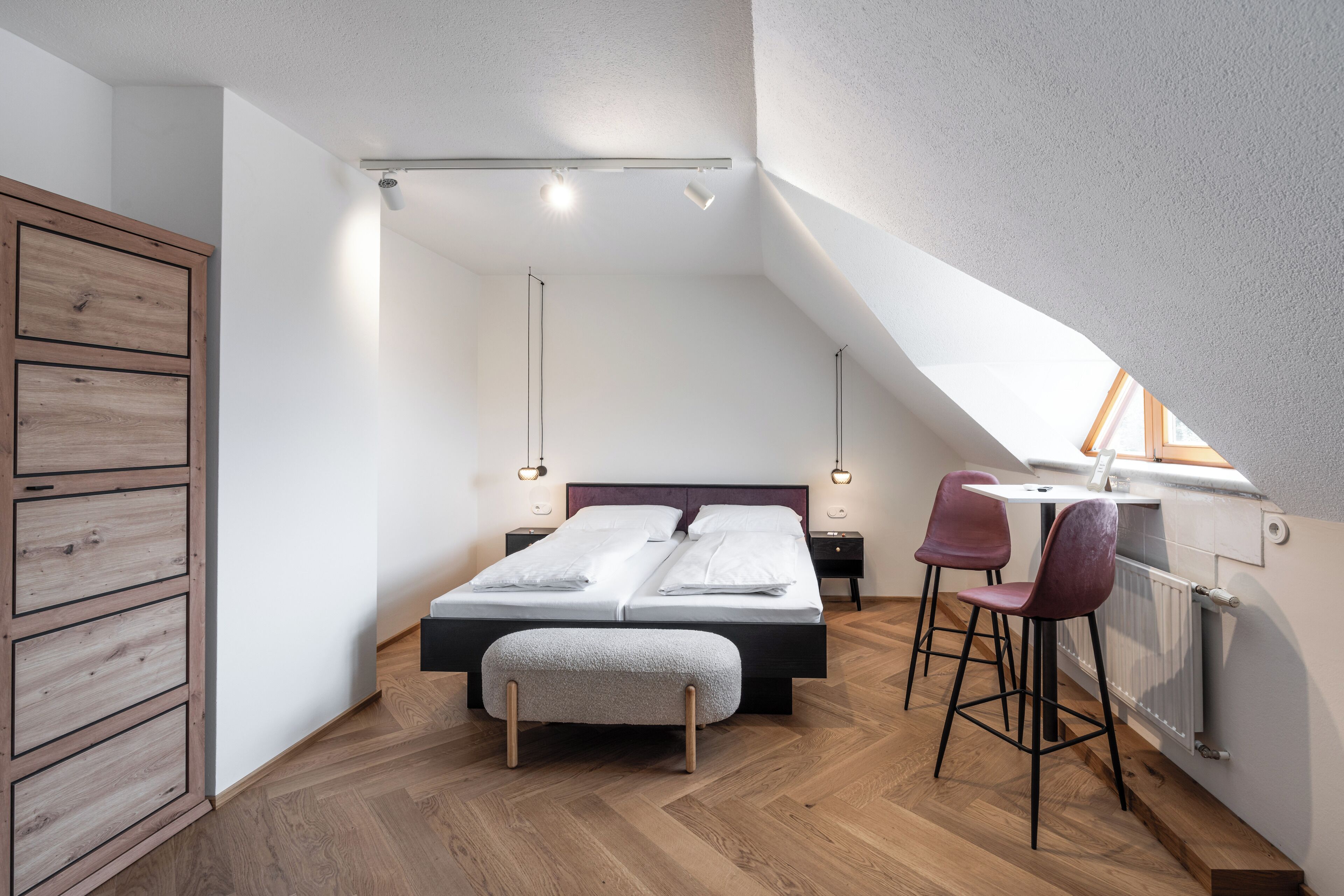 Un dormitorio con cama, mesitas de noche, un escritorio con silla y un radiador.