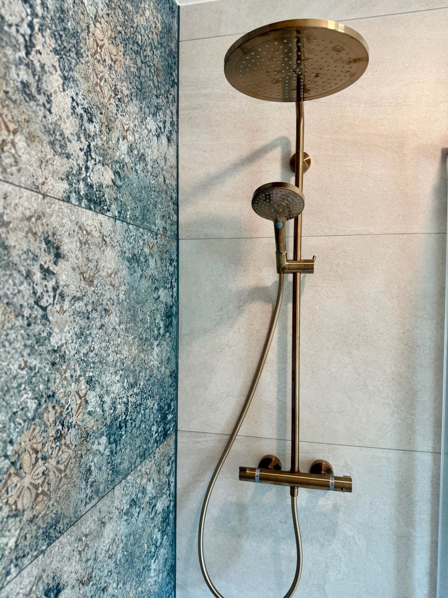 A modern shower with a handheld showerhead and a wall-mounted control panel.