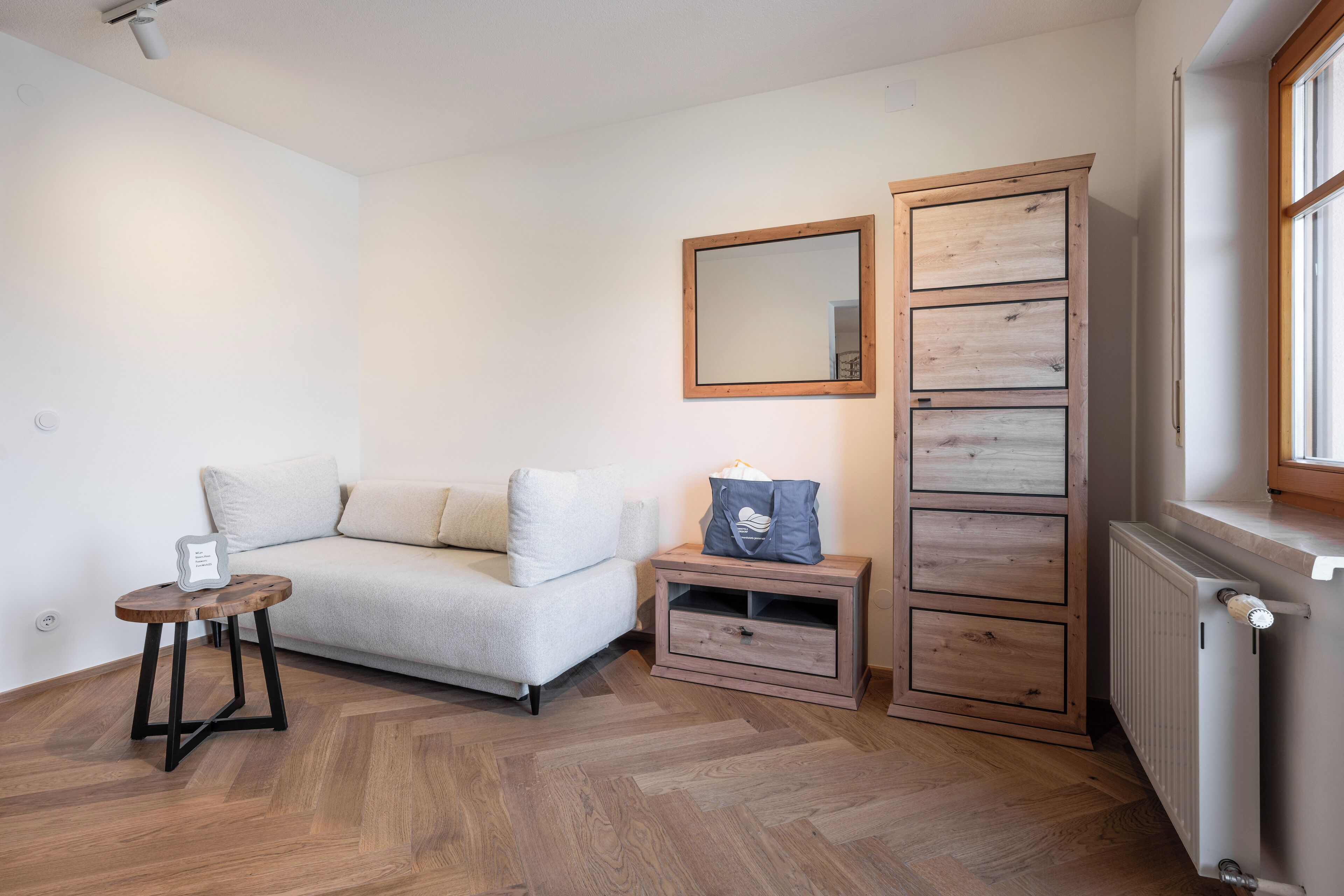 A room with a sofa, a small table, a cabinet, and a radiator.
